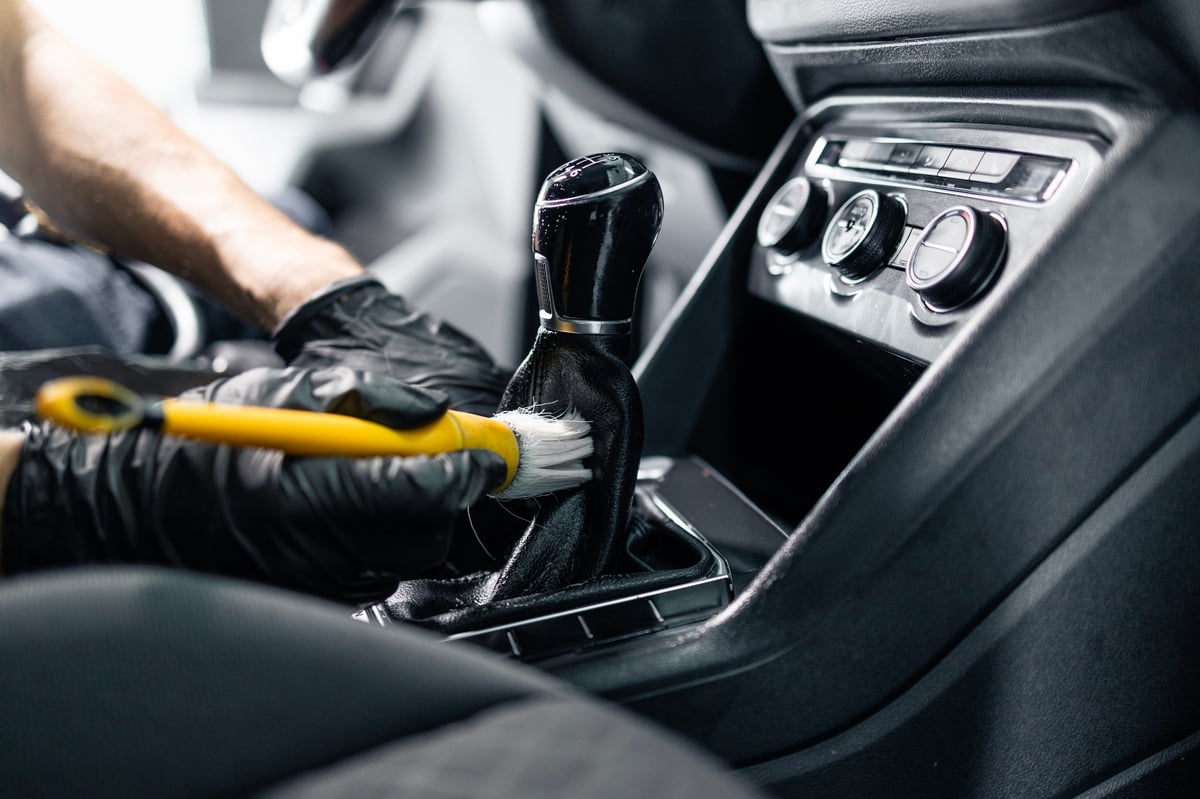 Detailer using a soft brush to clean the inside of a car interior