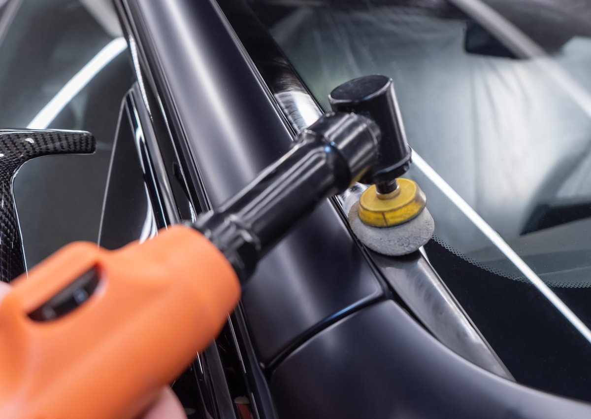 Close-up of a machine polisher restoring a car's paint to a deep gloss