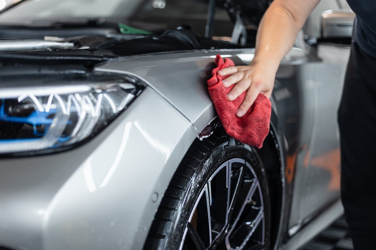 Professional detailer wiping and drying a car by hand
