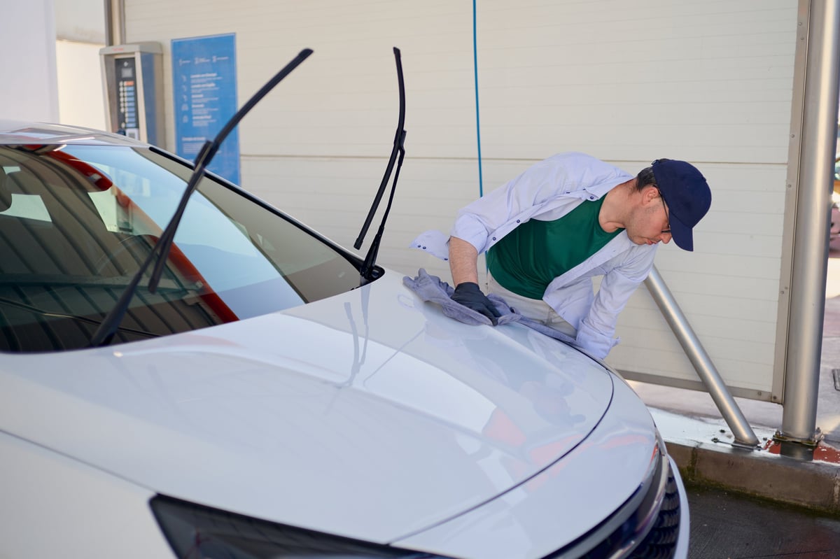 Detailer drying a white car hood with a microfiber cloth for a spotless finish